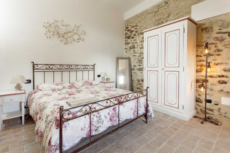 Camera semplice con letto in ferro battuto, dotata di decorazioni rustiche. Ideale per momenti di relax.