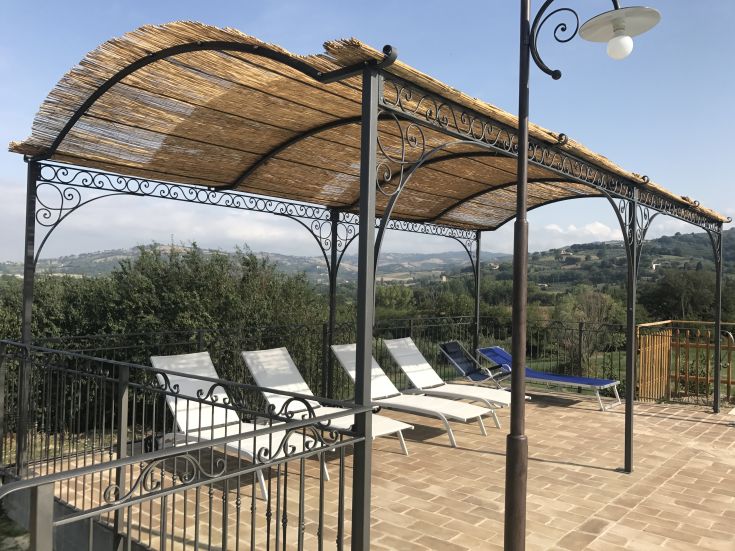 Area relax ombreggiata con lettini comodi, affacciata sulle colline umbre.