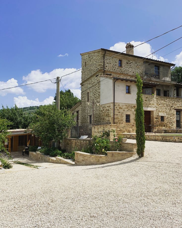 Un agriturismo in pietra circondato da un paesaggio verde tipico dell'Umbria.