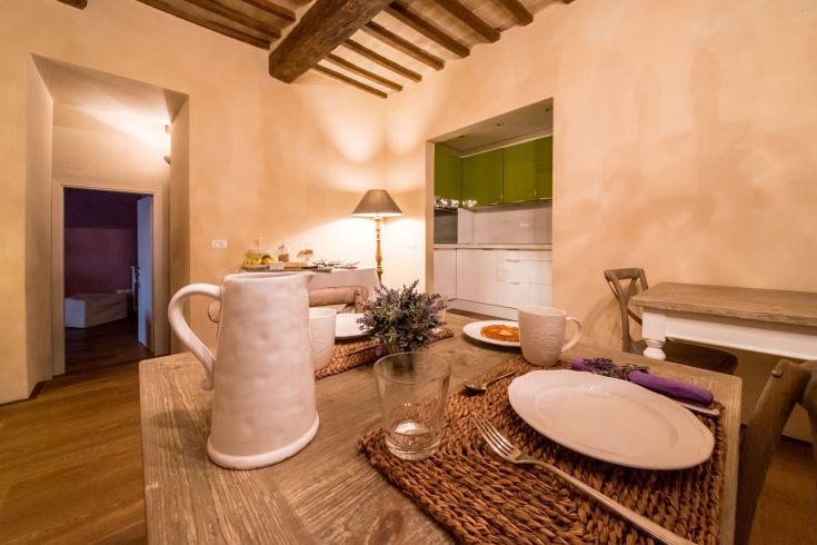 A simple room with a set dining table, illuminated by a lamp.