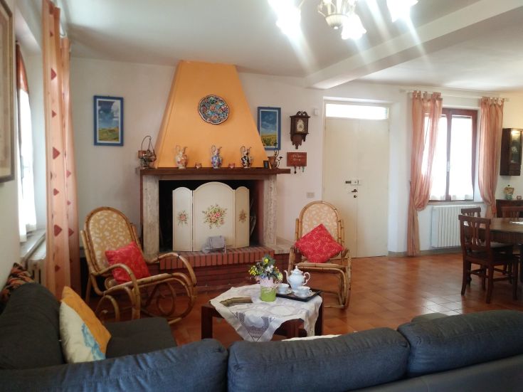 A cozy and bright living room with a working fireplace, simply furnished for relaxation moments.