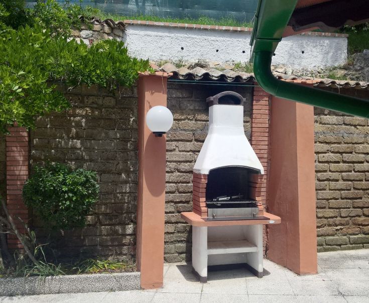 Barbecue area in a garden surrounded by plants, perfect for outdoor relaxation moments.