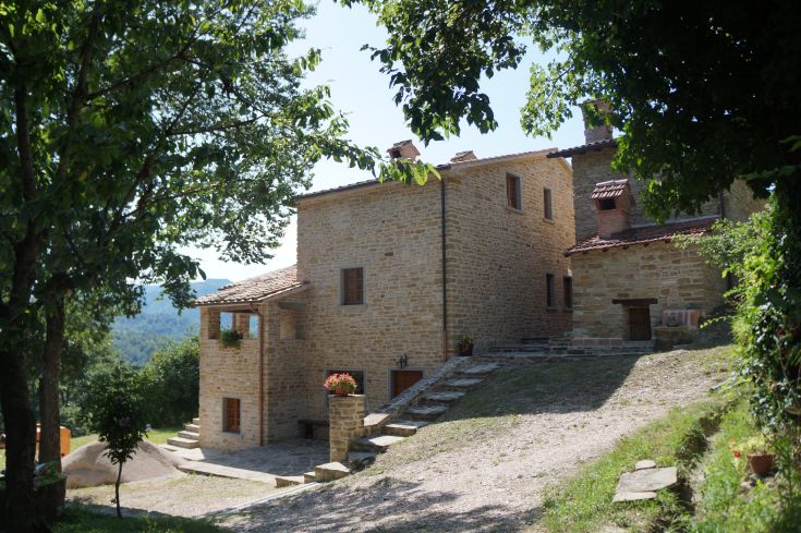 Une ferme accueillante nichée parmi les collines de l'Apennin, entourée de bois verdoyants.