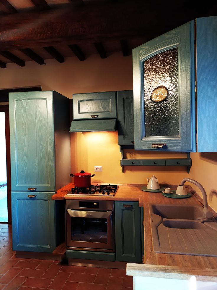 Une cuisine accueillante avec des placards bleus, une casserole rouge et un plan de travail en bois.