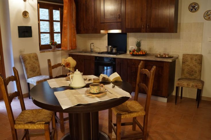 Cuisine spacieuse avec une table ronde en bois, des décorations simples et des fruits frais dans un panier.