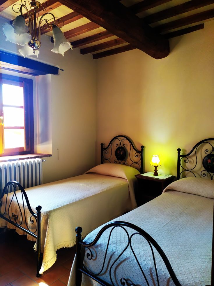 Chambre avec deux lits simples et une lampe, présentée dans une tonalité chaude et lumineuse.