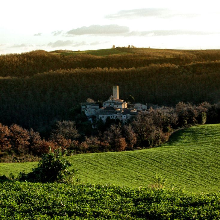Ein ruhiges Dorf, umgeben von grünen Hügeln und Bäumen, eingebettet in die umbrische Natur.