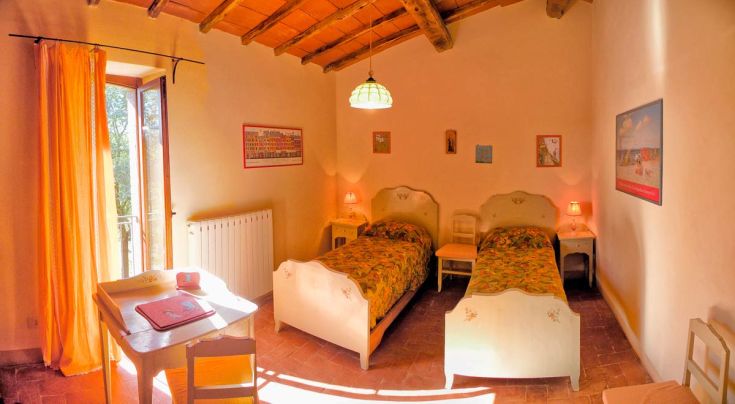 Einfaches Zimmer mit Einzelbetten, lebendiger Dekoration und natürlichem Licht, ideal für einen ruhigen Aufenthalt.