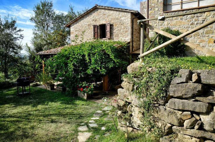 Ein elegantes Steingebäude mit Einzelapartments, Schwimmbad und Wellnessbereich, umgeben von Grün.