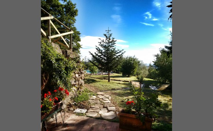 Ein Landhaus, eingebettet in die Natur, mit einem Weg zu einem gepflegten Garten und einem Blick auf die umliegende Natur.
