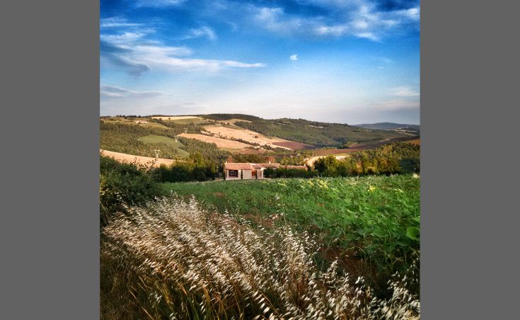 Ein steinernes Gebäude, umgeben von grünen Hügeln, mit unabhängigen Apartments und einem entspannenden Schwimmbad.