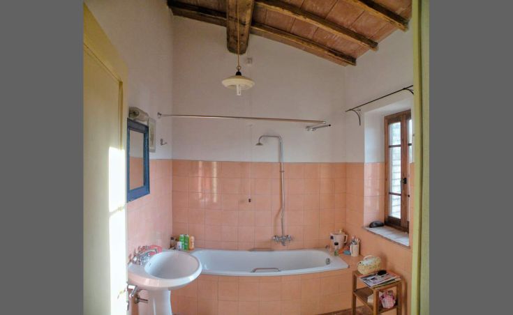 Ein intimes Badezimmer mit Badewanne, rosa Fliesen und sanfter Beleuchtung.