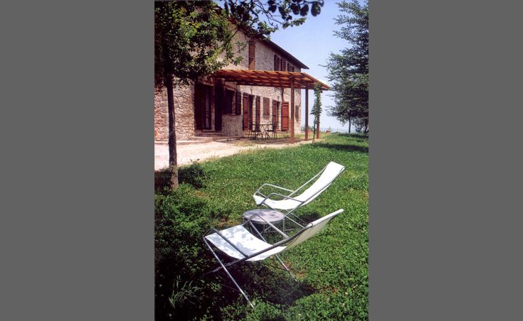 Ein Steingebäude mit Garten und Liegestühlen, ideal für entspannende Momente und kurze Aufenthalte.