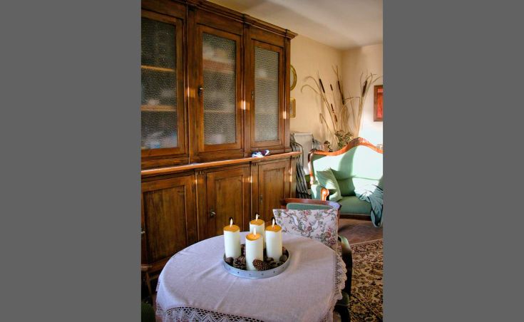 Ein ordentliches Wohnzimmer mit Holzmöbeln und einigen Kerzen auf einem Couchtisch. Eine ruhige und entspannende Umgebung.