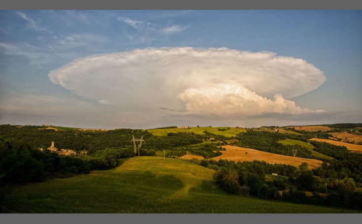 Sanfte Wolken schweben über eine grüne Hügellandschaft und zeigen die Harmonie der Natur.