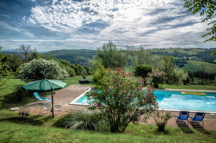 Entspannen Sie sich am Pool in einem weitläufigen Garten und genießen Sie die umliegende Landschaft.