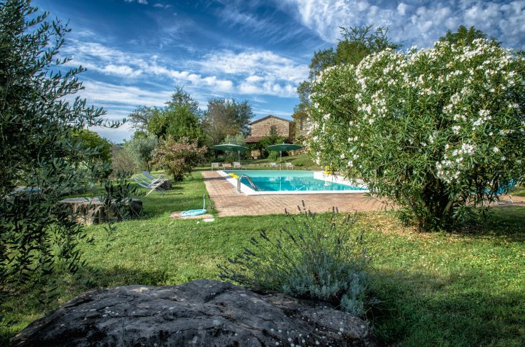 Steinbau mit einfachen Apartments, einem Außenpool und einem Entspannungsbereich inmitten von Grünflächen.