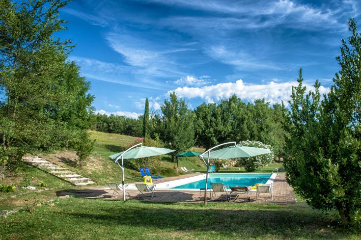 Außenbereich mit einem von Grün umgebenen Pool, ideal für Familien und Gruppen.