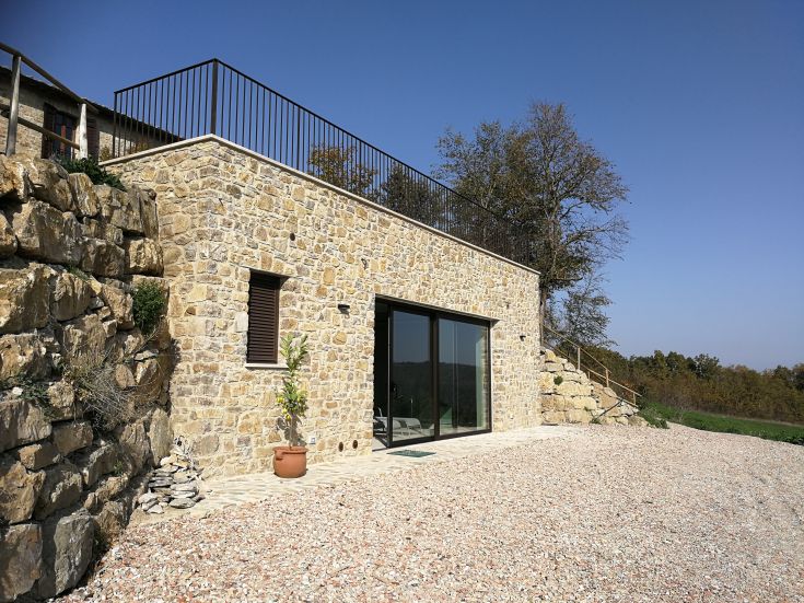 Ein steinernes Gebäude mit vier unabhängigen Wohnungen, einem Außenpool und einem Wellnessbereich in der Natur.