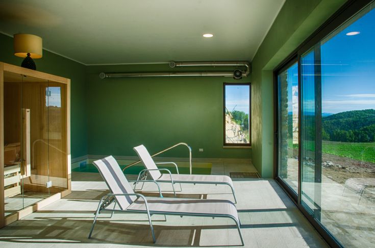 Ein einladender und gut beleuchteter Wellnessbereich mit Liegen und Sauna, ideal zum Entspannen und Wohlfühlen.