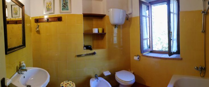 Funktionales Badezimmer in einem renovierten Gebäude, mit einem einfachen Design und Fenstern, die natürliches Licht fördern.