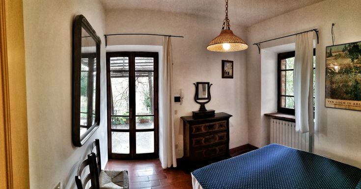 Gemütliche Wohnung mit Fenstern, die auf grüne Flächen blicken, einfach eingerichtet.