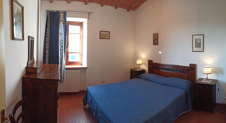 Ein ruhiger Raum mit einem Doppelbett, Holzmöbeln und warmen Farbtönen für eine gemütliche Atmosphäre.