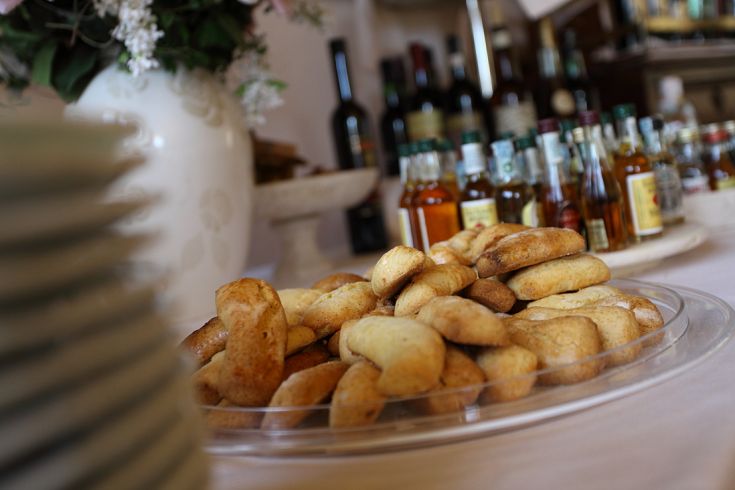 Cookies served on a tray, accompanied by several bottles of liqueurs in the background.