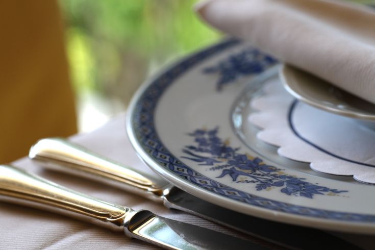A beautifully set table with decorative plates and shiny metal cutlery.