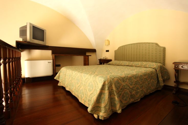 Simple hotel room featuring a double bed and TV, perfect for a relaxing stay.