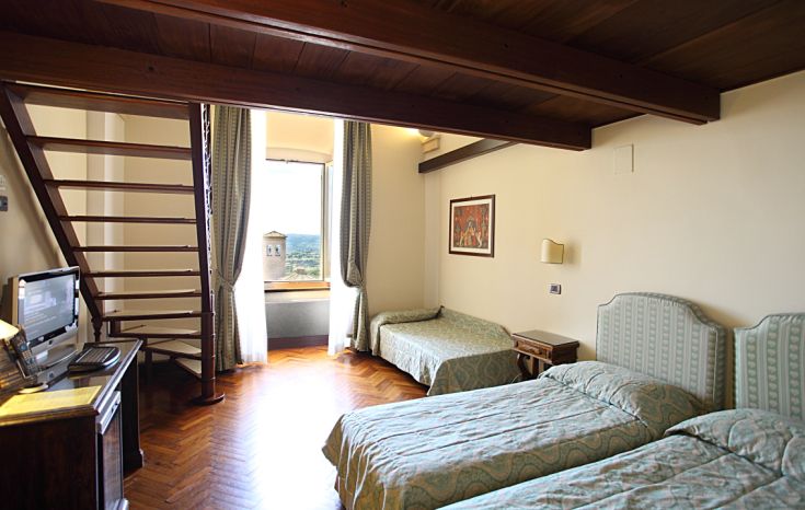 Simple room with a panoramic view of a vast landscape, furnished with wooden furniture.