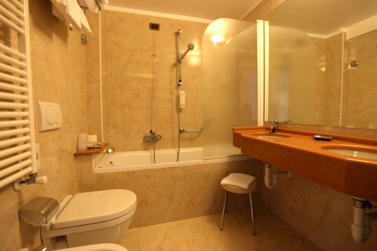 Recently renovated bathroom with a bathtub and shower, featuring light marble finishes.