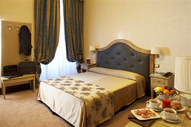 Camera ben arredato con letto matrimoniale, dettagli decorativi e un piccolo angolo per la colazione.