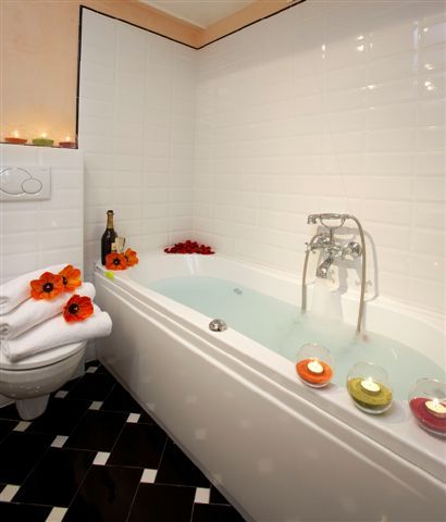 Un bagno semplice con vasca, decorato con piante e candele, ideale per momenti di relax.