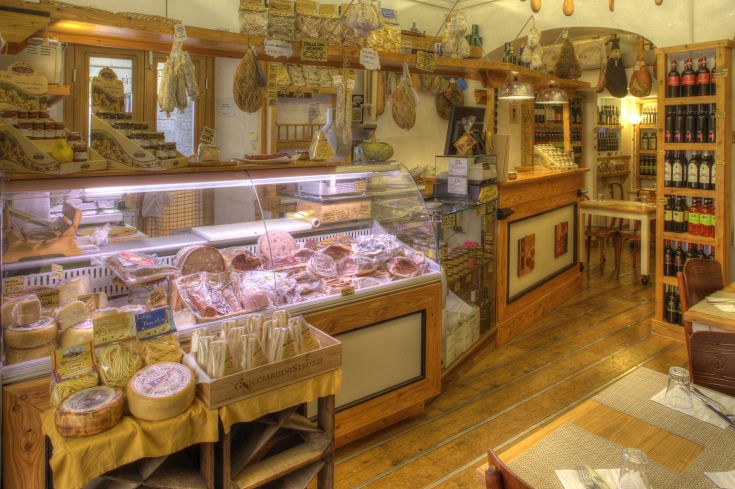 Un negozio di alimentari che offre prodotti locali, come salumi e formaggi, in un contesto familiare.