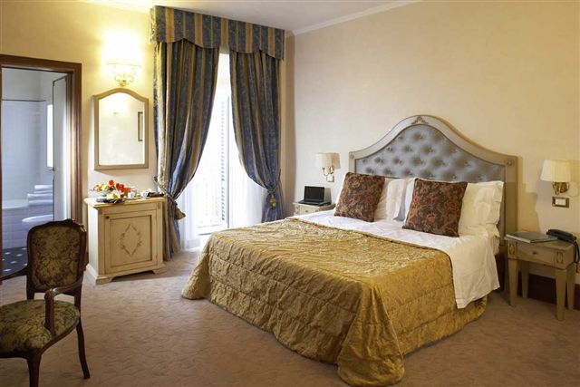 Camera raffinata con letto matrimoniale e arredamento classico, affacciata su un bel panorama di Assisi.