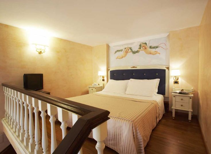 Camera spaziosa con arredi semplici e affreschi, luminosa e accogliente.