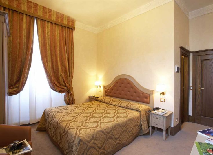 Camera con letto matrimoniale e tendaggi, adatta per un soggiorno confortevole.