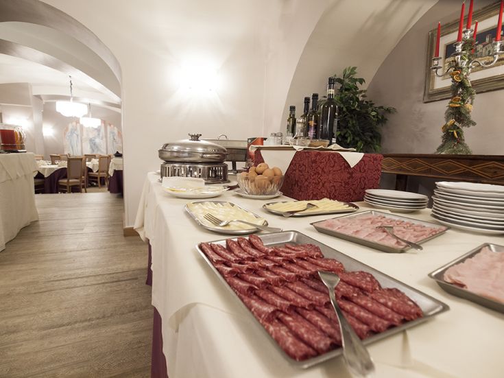 Un buffet ben fornito di salumi, formaggi e piatti tipici, inserito in un ambiente curato e accogliente.
