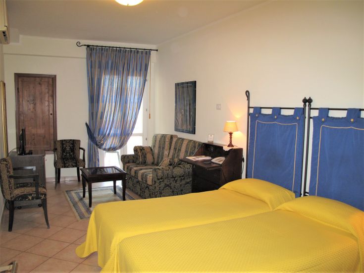 Geräumiges Hotelzimmer mit zwei Einzelbetten und einem Wohnbereich, perfekt für entspannende Momente.