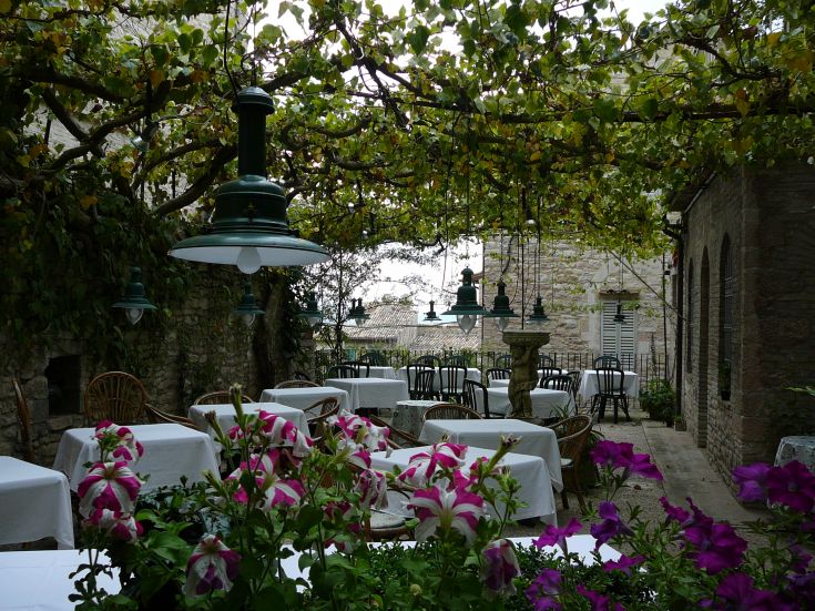 Ein Restaurant im Freien mit arrangierten Tischen und grünen Pflanzen, die eine einladende Atmosphäre schaffen.
