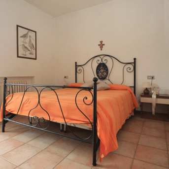 Camera confortevole in stile rustico, con letto in ferro e colori caldi. Ottima per momenti di relax.