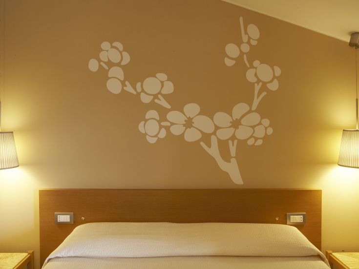 Stanza con decorazioni floreali su una parete e lampade che creano un'atmosfera calda e confortevole.