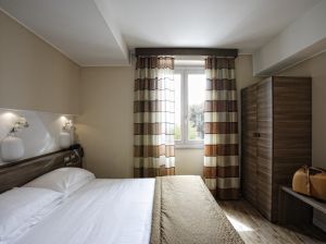 Camera moderna e luminosa con panorama sulla valle, arredamento sobrio e comfort adeguati.