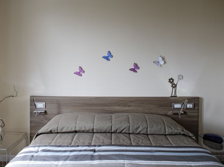 Camera confortevole con pareti decorate da disegni di farfalle. Atmosfera tranquilla e accogliente.