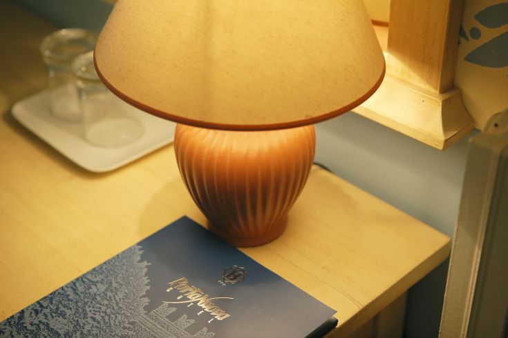 Una lampada accesa illumina una scrivania, con un menù posato accanto, creando un'atmosfera tranquilla.