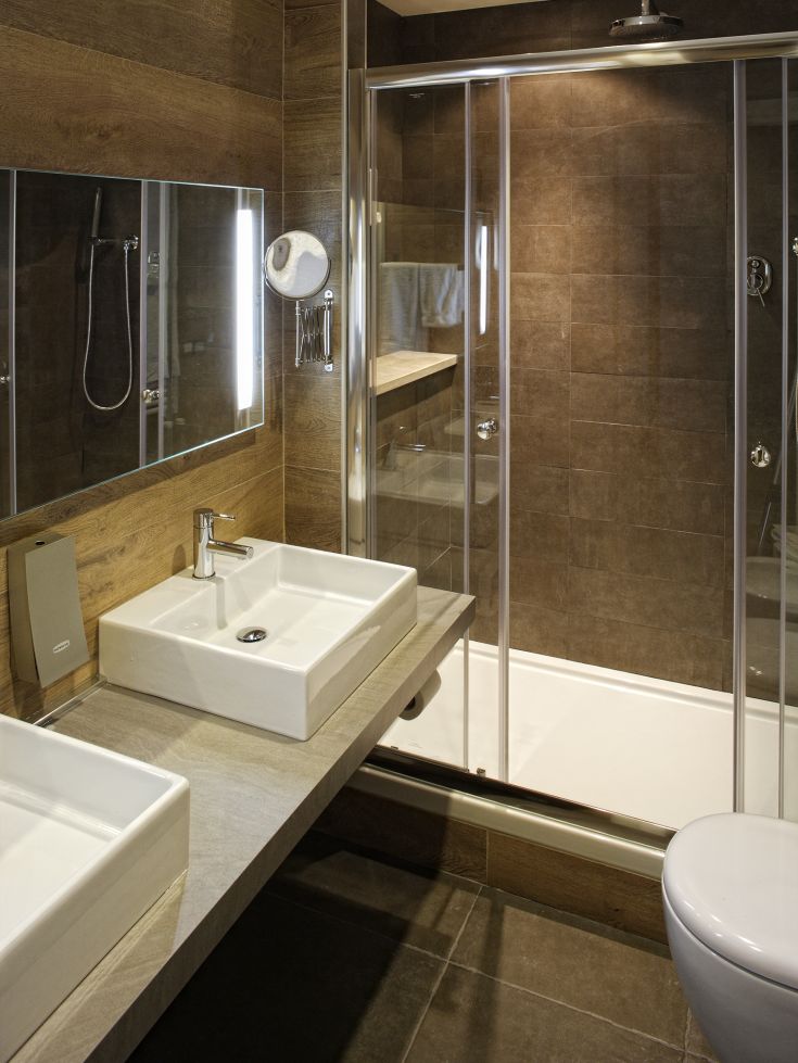 Bagno contemporaneo con piastrelle in ceramica e due lavabi. Cabina doccia in vetro trasparente.