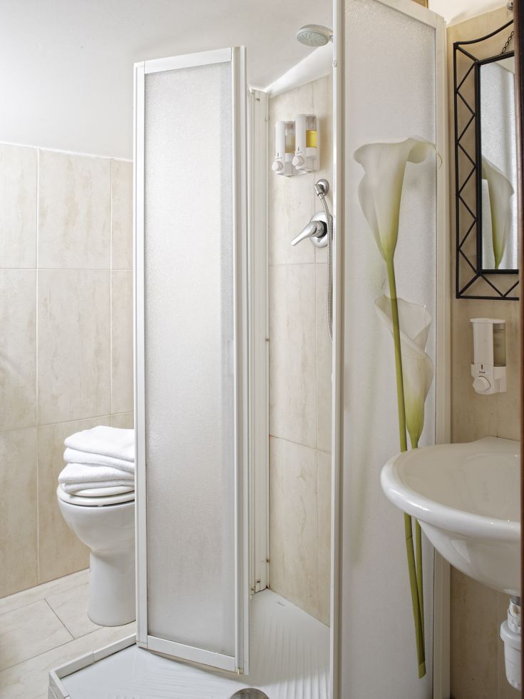 Un bagno elegante con doccia, lavabo e servizi igienici, caratterizzato da tonalità neutre e dettagli semplici.