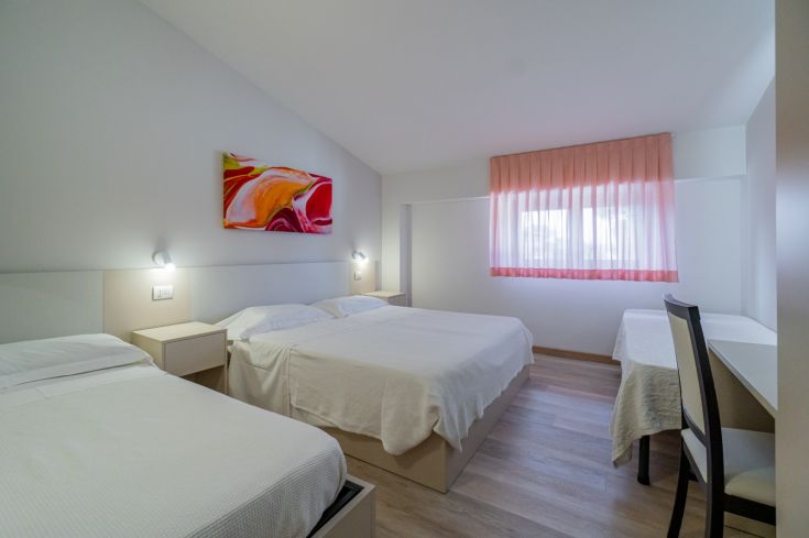 Camera semplice e tranquilla con letti comodi e arredamento sobrio, perfetta per un soggiorno rilassante.