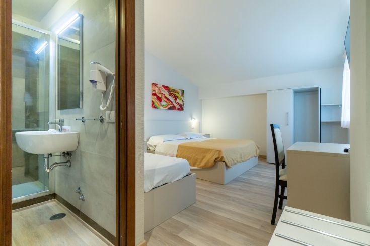Camera confortevole dell'hotel con letti e bagno moderno. Arredi semplici e atmosfera rilassante.